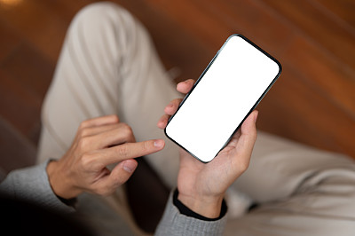 一名男子坐在房间里使用智能手机的特写照片。使用应用，发短信，回复信息