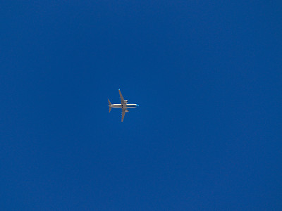 jet plane, flying at high altitude, crossing a cloudless blue sky.