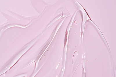 液体凝胶涂抹离子粉红色背景。美容化妆品污物，如纯透明芦荟乳液，面部啫喱精华液，洗面奶，沐浴露或洗发水俯视图