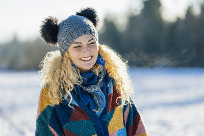 幸福的女人在冬天森林附近的白雪皑皑的草地