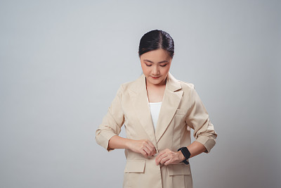 一个亚洲女人开心地笑着，整理着她的衣服，孤立在背景中。