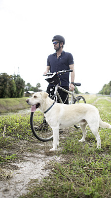 骑自行车的人带着狗，骑自行车的人带着他的大品种狗散步