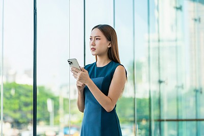 年轻的亚洲女子用手机看向别处，一副担忧的表情