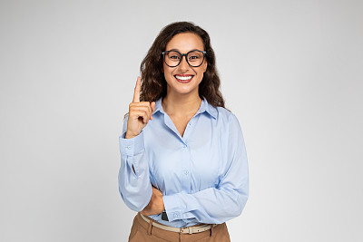 微笑自信的千禧一代白人商务女士，穿着正装戴着眼镜的老师指着空余的空间