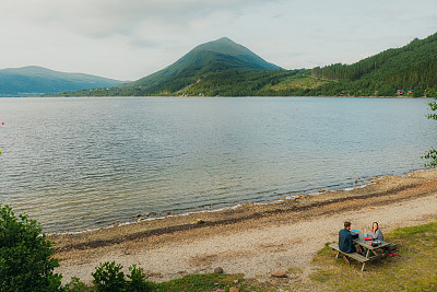 鸟瞰图的女人和男人欣赏野餐的湖与山景