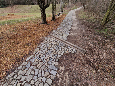 花岗石板铺成不规则的碎石段，公园四周有一条带有绿色草坪的灰色人行小道，湿滑的小道上有楼梯，是一条狭窄的捷径
