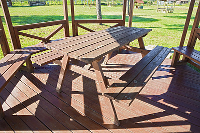 Wooden picnic table in a wooden gazebo on a green meadow in a public park