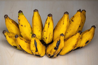 一串熟透的黄香蕉放在木制背景上。香蕉富含钾和其他重要的矿物质和维生素，可以帮助你的身体发挥关键功能。
