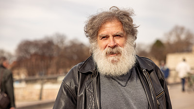 一个年长的白人男子的肖像，在城市里，有一头长长的白发和胡子