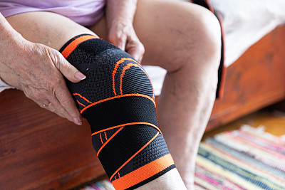 老人的手放在膝盖上，腿放在护膝上，老人的胳膊和腿酸痛，关节炎和关节疼痛