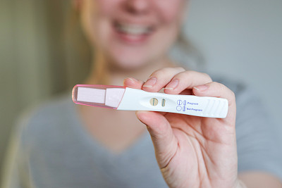 一个快乐的女人拿着怀孕测试呈阳性的特写