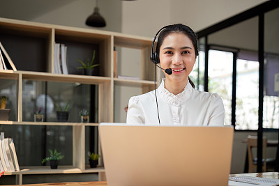 客服中心友好的亚洲女性负责客户服务，技术支持和建议，与客服中心的员工接线员联系和沟通