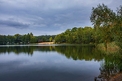 湖的自然景观，清晰度高，运动的波浪衬托着秋天的森林。云在水波上的倒影。德国。