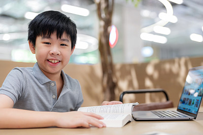 周末，一个亚洲男孩坐在共享办公空间里，全神贯注地看书。学生致力于自我学习和个人发展，在轻松和现代化的学习环境中突出他的注意力和专注力。