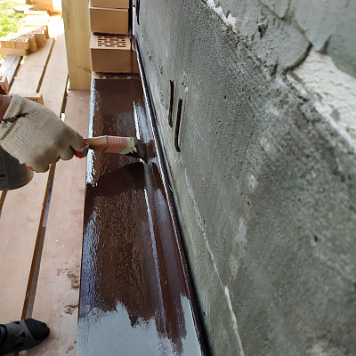 一名在建筑工地工作的男子用棕色油漆把金属角涂上。