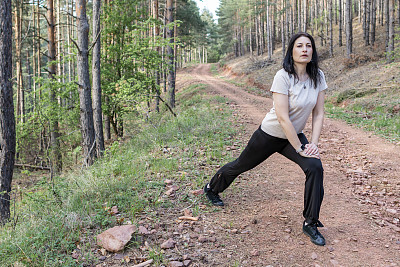 快乐的女跑步者正在森林里阳光明媚的小路上享受慢跑或越野跑。