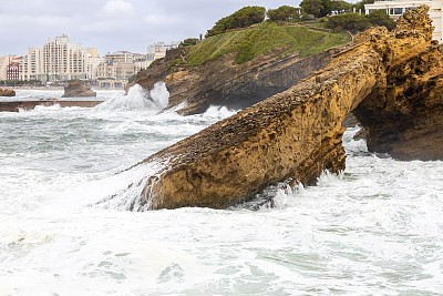 海浪拍击着黄色的岩石，狂风大作。比亚里茨,法国。