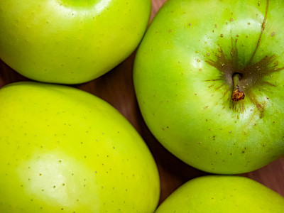 在中性的背景上，有新鲜光泽的青苹果，有些带有棕色斑点。
