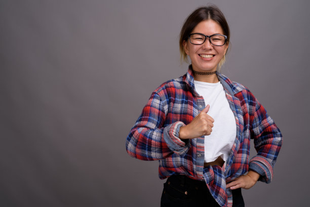 工作室拍摄的年轻亚洲妇女穿着格子衬衫，以灰色背景
