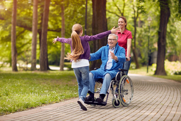 坐在轮椅上的快乐的残疾祖父欢迎他的孙女