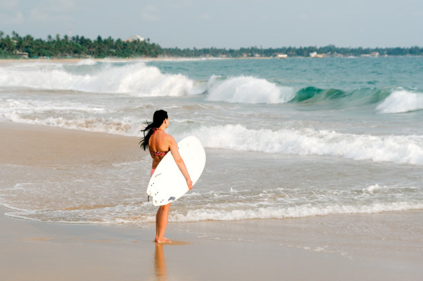 年轻的冲浪者站在海滩上拿着冲浪板。斯里兰卡。弥留的