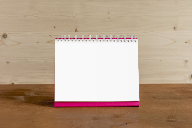 白色空白纸桌上螺旋日历上的木材背景。