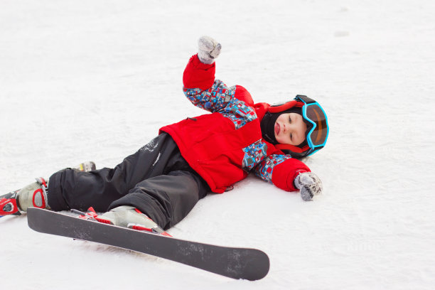 带着滑雪板和滑雪服的可爱小男孩。