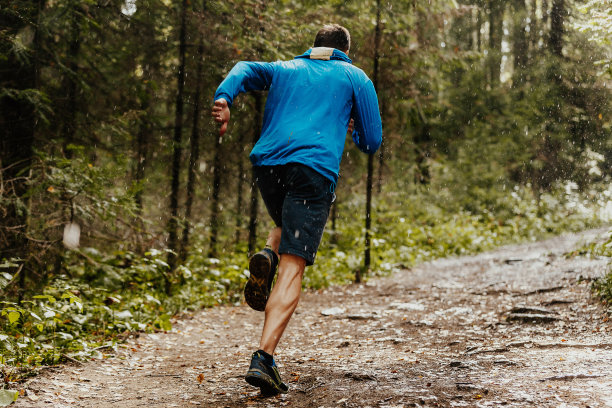 肌肉发达的男性跑步者在雨中快速奔跑森林小径