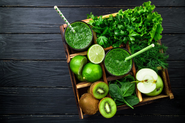 深色木质背景上的绿色冰沙。健康的冰沙鸡尾酒。绿色蔬菜和水果。健康饮食理念。俯视图