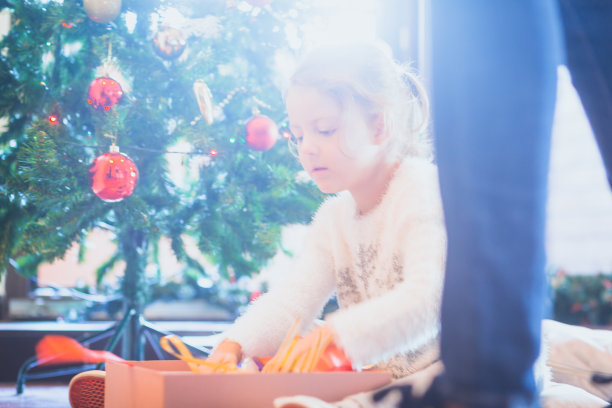 圣诞节。剪小女孩与圣诞礼物盒和装饰的乐趣。她正坐在家里装饰圣诞树。贝尔格莱德,塞尔维亚,欧洲