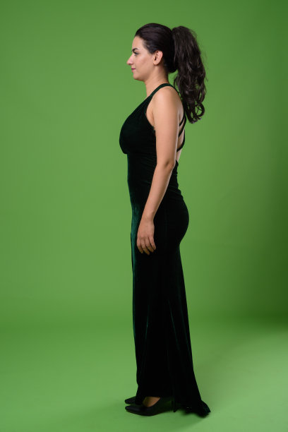 美丽的伊朗女人穿着黑色无袖连衣裙，以绿色为背景