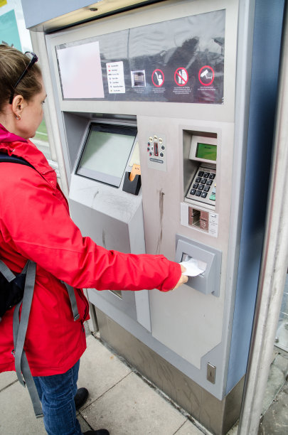 秋日，一名女子在火车站外的自动售票机旁购买火车票或公交车票