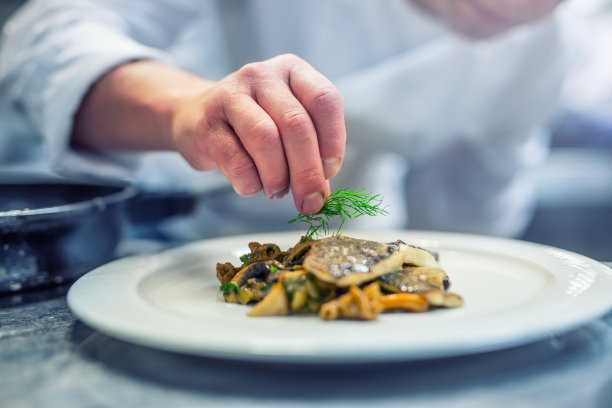 厨师在酒店或餐厅厨房做饭，只用手。配以莳萝装饰的鱼排