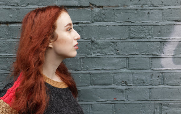 华丽的红发英国秋天户外女孩的侧面墙上涂鸦