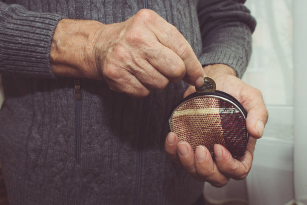 一位老人把一枚硬币放进一个空钱包里。贫困的退休概念。特殊的爽肤水
