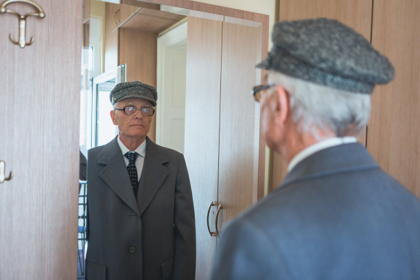 老年人在家里。老男人看着镜子，穿衣服