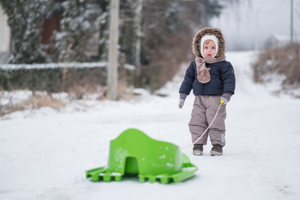 可爱的小男孩在雪地上拉雪橇