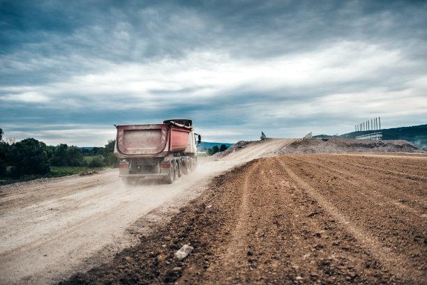 工业自卸车在公路施工现场装卸砂砾和泥土。