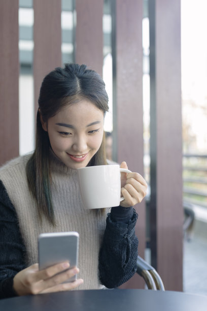 女人一边喝咖啡一边看手机