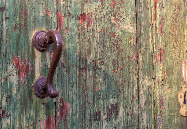 古董门把手和木门。门上的油漆裂了，脱落了。