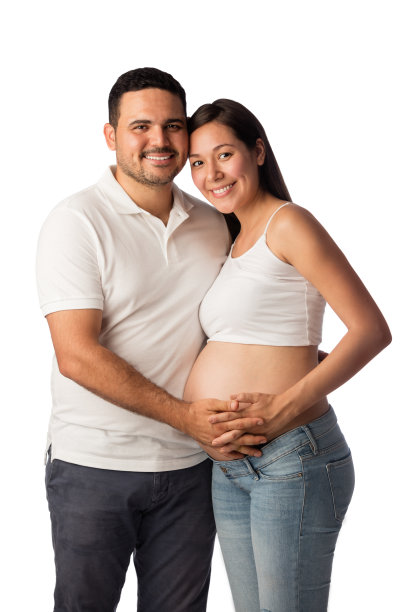 一对怀孕的夫妇站在一起，对着镜头微笑