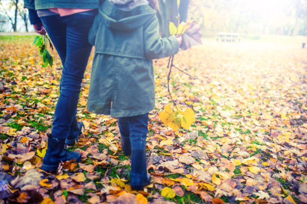 秋天的公园里，妈妈和女儿手牵着手走着