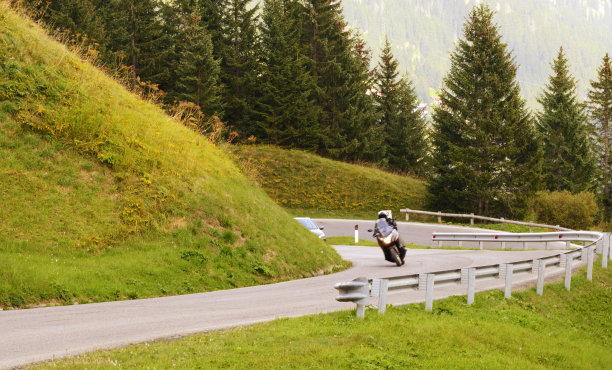 在欧洲阿尔卑斯山的山路上骑摩托车的人。