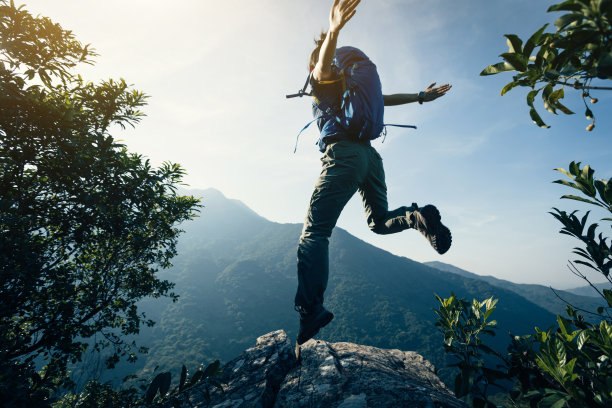 成功的女背包客在悬崖边上跳