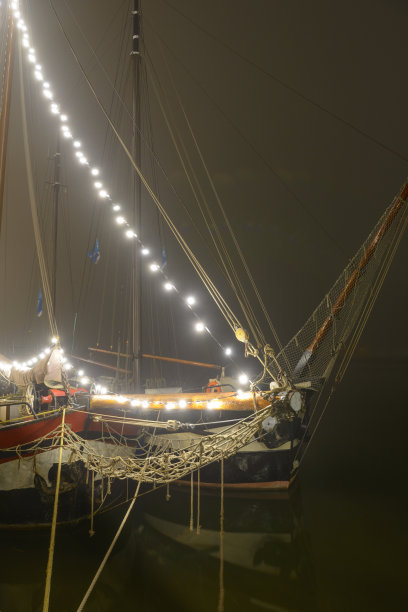 在一个雾蒙蒙的夜晚，古典帆船停泊在坎彭的码头上