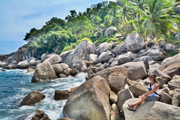 西方女人从旅游中放松下来，在泰国Ko Tao的岩石海岸享受海景