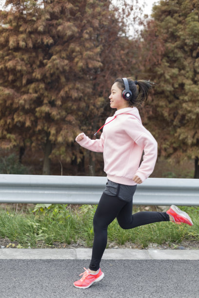 年轻女子在柏油路上伴着音乐奔跑