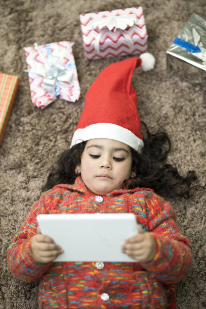 戴着圣诞帽的小女孩在用平板电脑