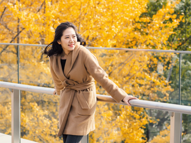 一个美丽的中国女孩的肖像站在金秋森林的背景。
