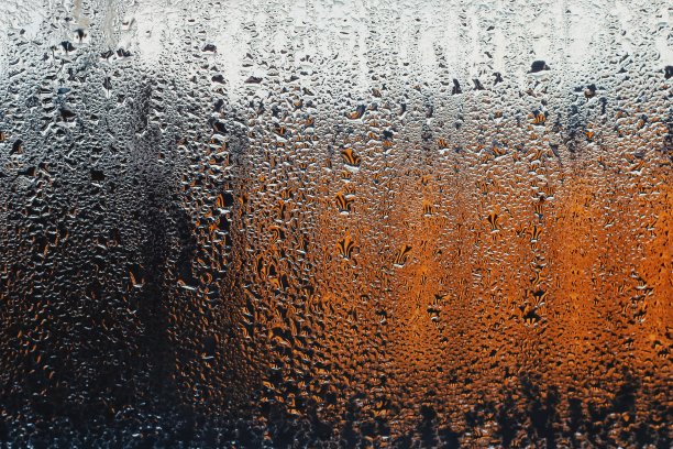 窗玻璃上的一滴水。背景是一个从黑色到白色再到橙色的渐变。浪漫而悲伤的背景
